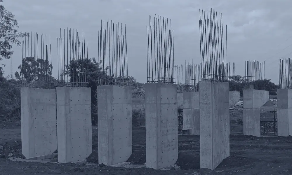 Pilares em concreto armado concluídos, com as barras da armadura de arranque expostas acima de cada pilar